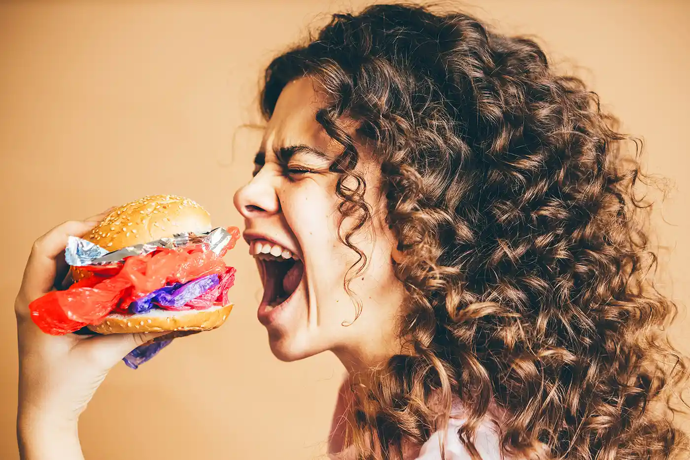 femme ouvrant la bouche prête à manger un burger avec du plastique pour réfleter