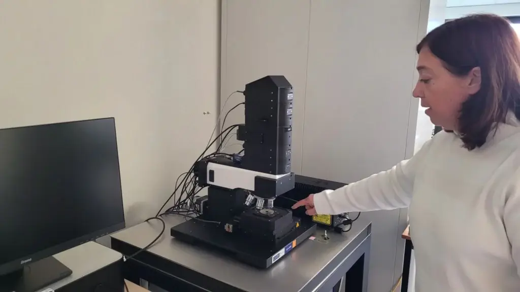 Chercheur montrant le microscope cellulaire sur un plan de travail au CBMN